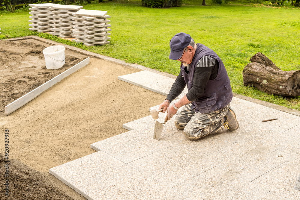 A worker is placing the concrete slabs floor. Groundwork and exterior paving. A worker is placing the concrete slabs floor. Groundwork and exterior paving.