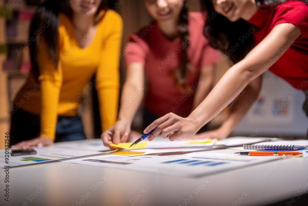 Fototapeta premium Marketing team working on project using sticky notes and brainstorming in office at night