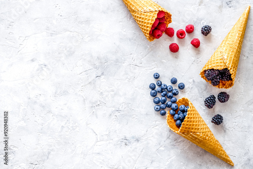 Summer breakfast with fresh berries in waffle cones on light sto photo