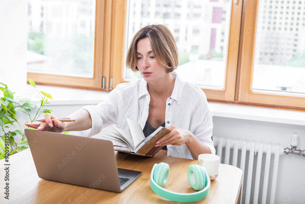 Young attractive woman sitting at the table and working on laptop at home Young attractive woman sitting at the table and working on laptop at home