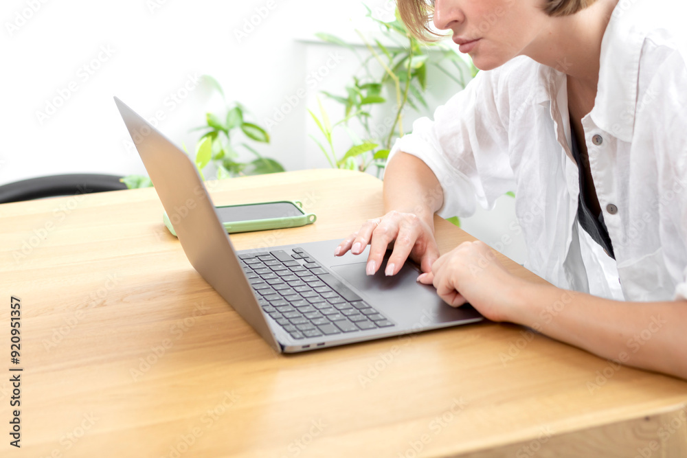 Young attractive woman sitting at the table and working on laptop at home Young attractive woman sitting at the table and working on laptop at home