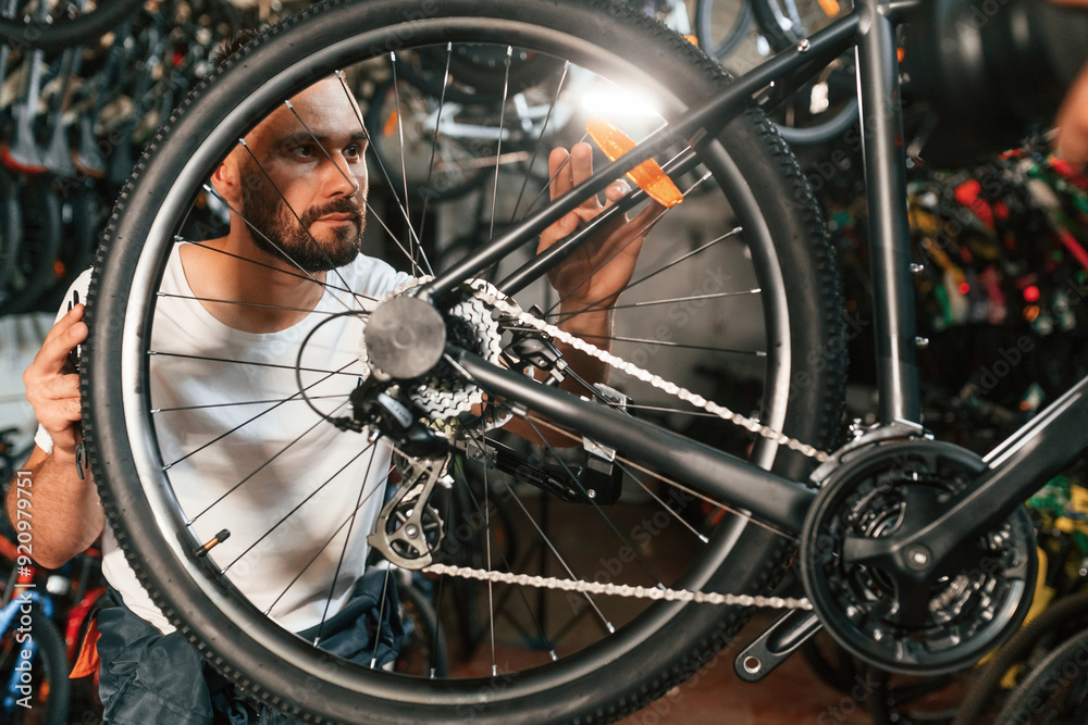 Rear wheel adjustment. Repair man in bicycle shop, working in store Rear wheel adjustment. Repair man in bicycle shop, working in store