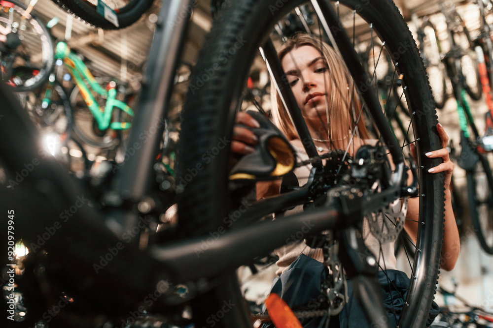 Obraz premium Repair woman in bicycle shop, working in store