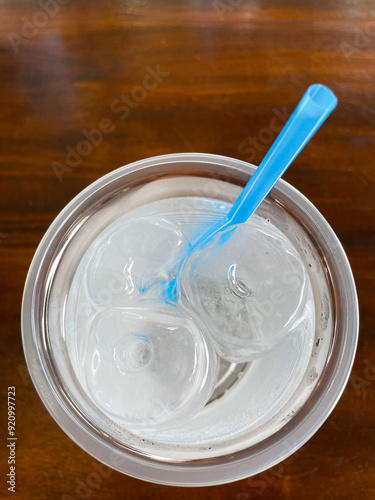 top view of ice and water in plastic glass on wood table in a restaurant