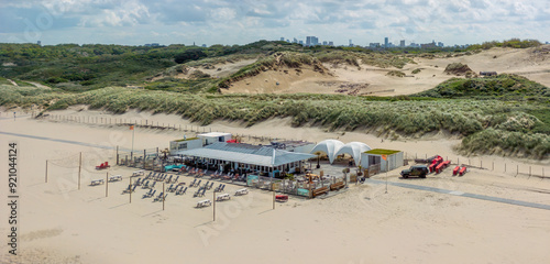 Fotografia A beachside venue is nestled among sand dunes with a cityscape visible in the distance