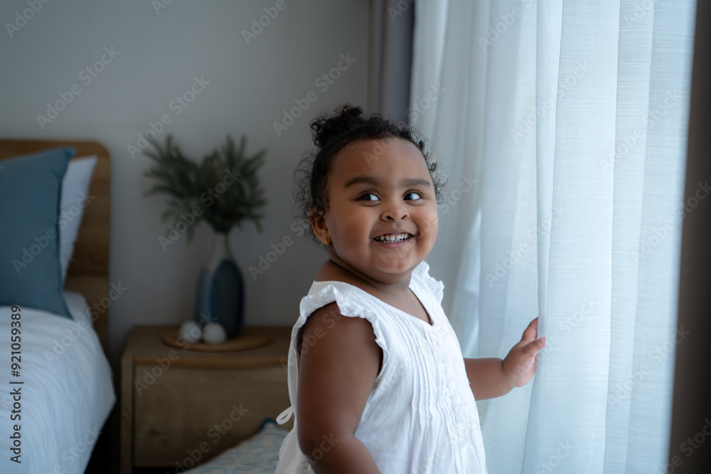 A tiny girl plays hide-and-seek with drapes in her bedroom A tiny girl plays hide-and-seek with drapes in her bedroom