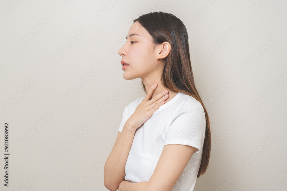 Sickness in inflaming asian young woman, girl use hand check self touch at sore throat, pain thyroid gland on neck or disease reflux, acid of suffer people on wall background. Medical and healthcare. Sickness in inflaming asian young woman, girl use hand check self touch at sore throat, pain thyroid gland on neck or disease reflux, acid of suffer people on wall background. Medical and healthcare.