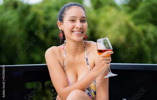 mujer joven sonriendo y disfrutando de una copa de vino al aire libre en vacaciones photo