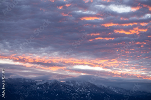 The sky, a canvas painted with strokes of ethereal pink, stretched across the horizon, casting a warm, rosy glow upon the tranquil landscape. The sky becomes filled with pink clouds over the mountains photo