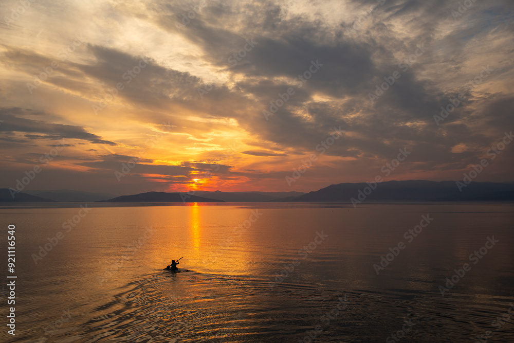 Kayaking off into the sunset on a large mountain lake Kayaking off into the sunset on a large mountain lake