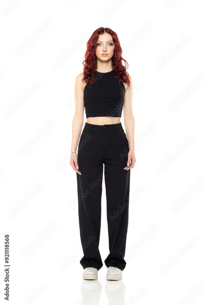 Charming young redhead woman posing in studio in black short blouse and black trousers on a white background Charming young redhead woman posing in studio in black short blouse and black trousers on a white background