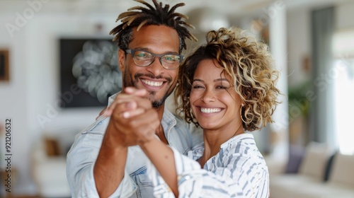 A joyful couple dances with smiles on their faces in a stylish and bright modern living room, radiating happiness and enjoying a shared moment of love and connection. photo