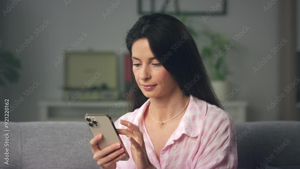 Pink blouse woman typing on smartphone at home Pink blouse woman typing on smartphone at home