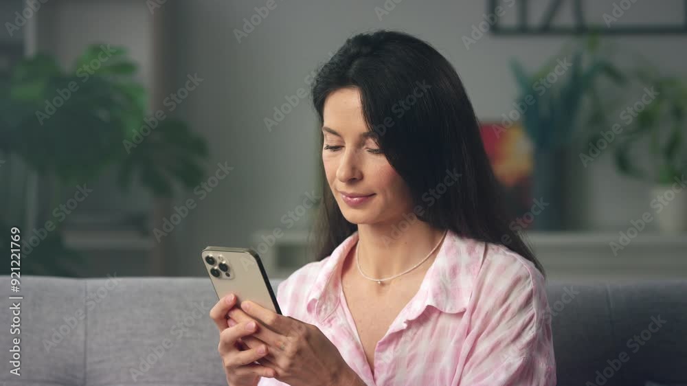 Smiling woman on sofa using smartphone at home Smiling woman on sofa using smartphone at home