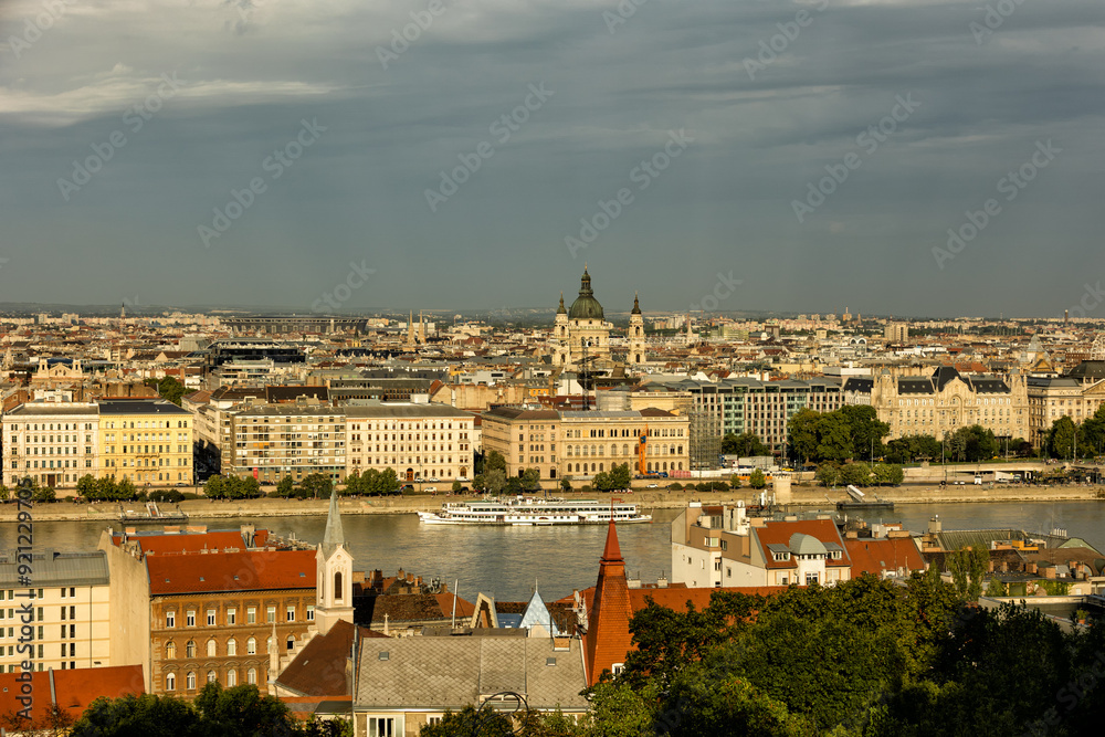 Obraz premium Budapest Hungary. View of the capital in Europe. Cruises ship passes on the Danube River. The imposing Parliament in the background. The bridges with cars, trams and bicycles. Concept photo