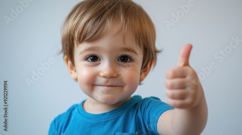 A young child is smiling and giving a thumbs up