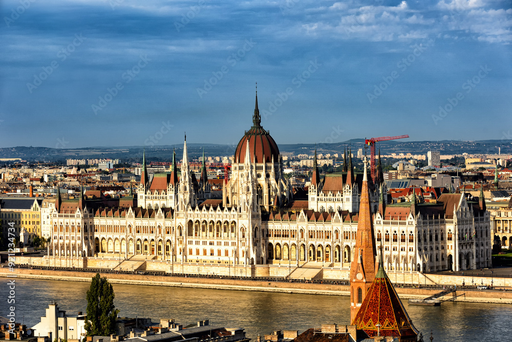 Obraz premium Budapest Hungary. View of the capital in Europe. Cruises ship passes on the Danube River. The imposing Parliament in the background. The bridges with cars, trams and bicycles. Concept photo