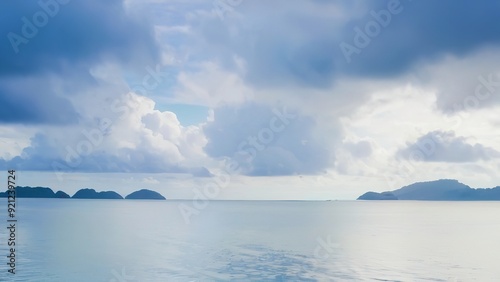 boats in the water with clouds overhead and a sky with small island in the background