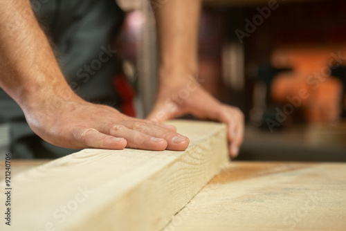 Close-up of an experienced carpenter, a man runs his hand over the wood that he has sanded.