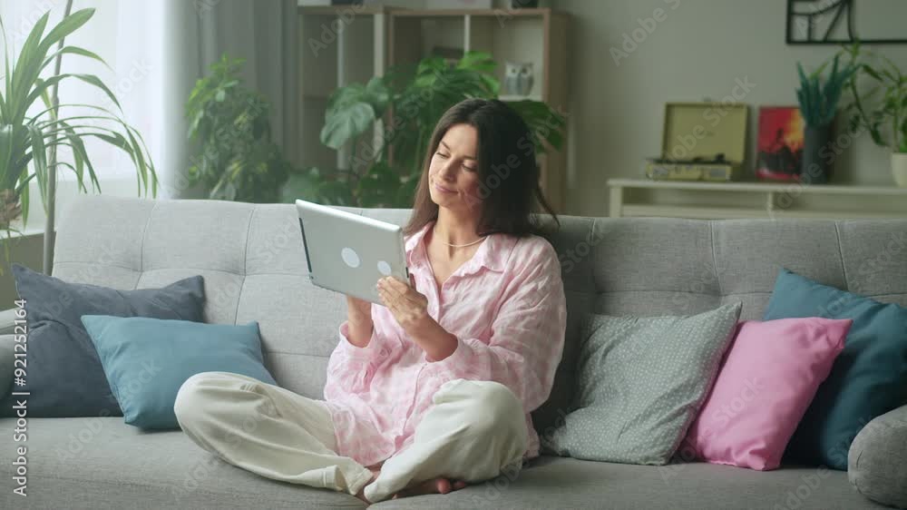 Cozy living room scene: woman using digital tablet on sofa Cozy living room scene: woman using digital tablet on sofa