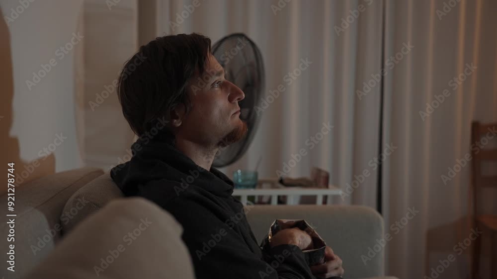 Thoughtful Munch, a man takes a moment to inspect his chip. The scene captures a quiet, contemplative evening. Thoughtful Munch, a man takes a moment to inspect his chip. The scene captures a quiet, contemplative evening.
