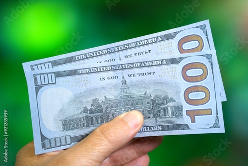 Mans hand holding 200 USD in fake or prop US 100 dollar bills