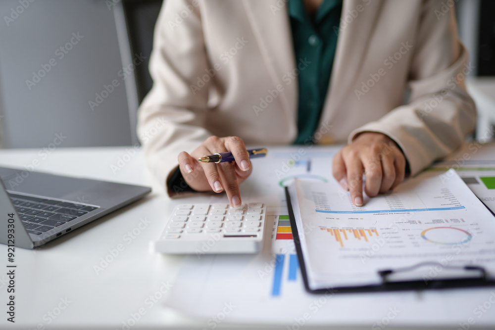 Businesswoman is calculating and analyzing financial data on a report at her desk Businesswoman is calculating and analyzing financial data on a report at her desk