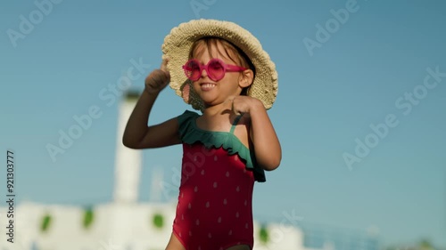 Funny little girl The girl is dancing on summer vacation. The child has fun on the beach. Cute baby in a colorful swimsuit and sunglasses is resting.