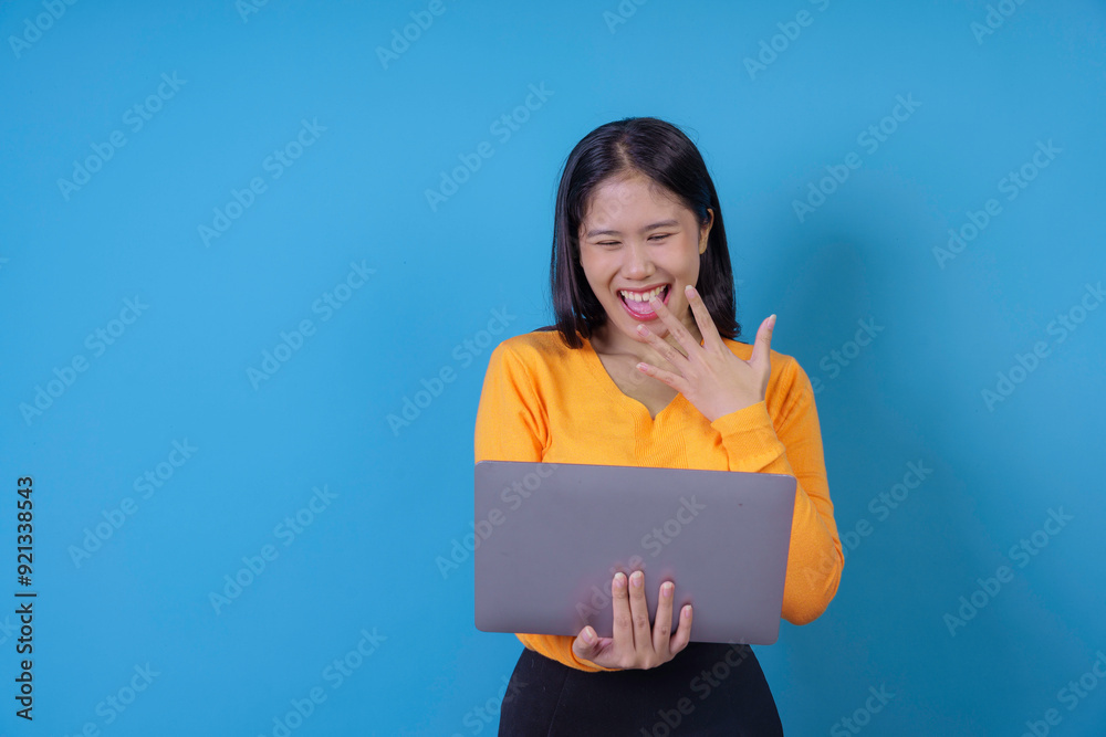 Young woman is covering her mouth while laughing at something she sees on her laptop Young woman is covering her mouth while laughing at something she sees on her laptop