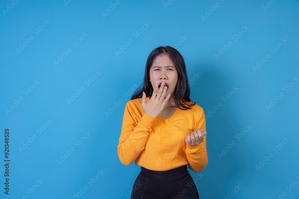 Young woman is yawning and covering her mouth with her hand, expressing tiredness or boredom Young woman is yawning and covering her mouth with her hand, expressing tiredness or boredom