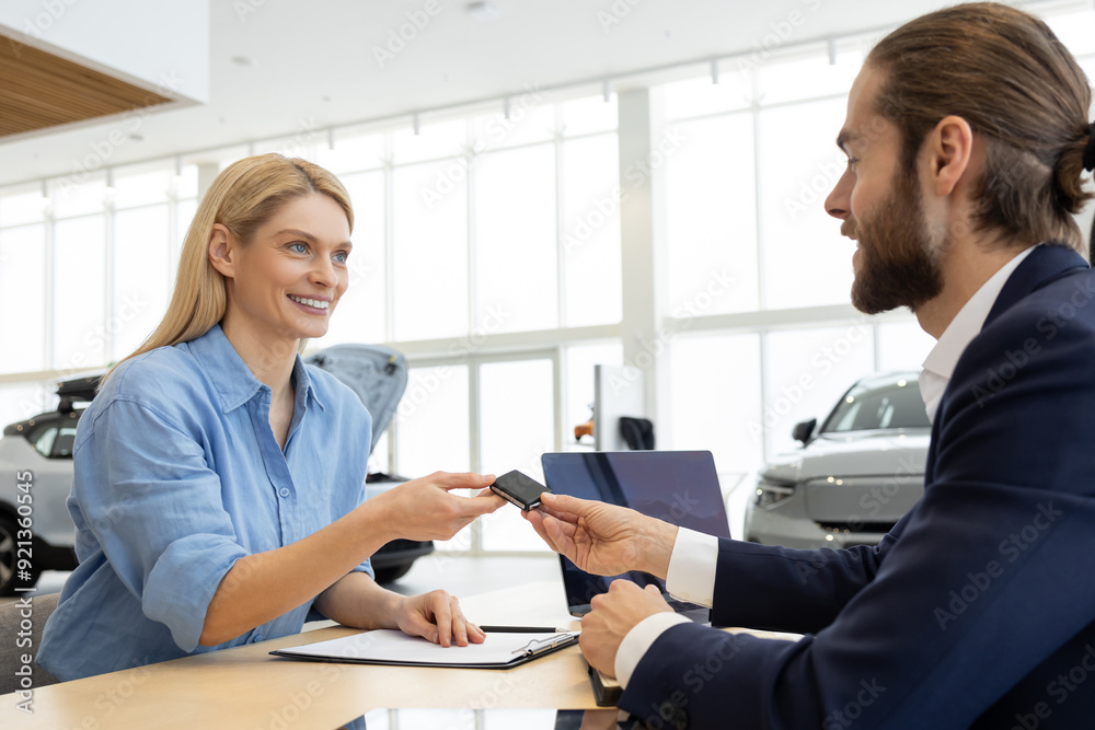 Rich woman customer client signing contract with salesman in car showroom Rich woman customer client signing contract with salesman in car showroom