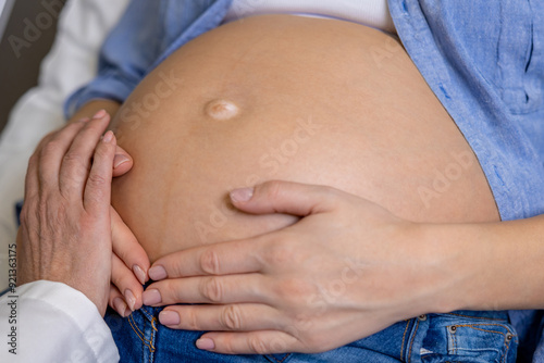 Close up of a pregnant woman on third trimester with hands on her belly photo