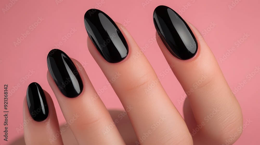 Close-up of hand with black glossy manicure on a pink background
