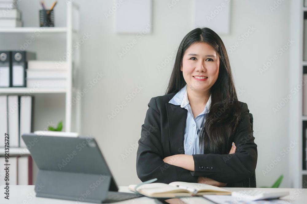 Asian businesswoman is smiling while sitting at her desk with her arms crossed in her office Asian businesswoman is smiling while sitting at her desk with her arms crossed in her office