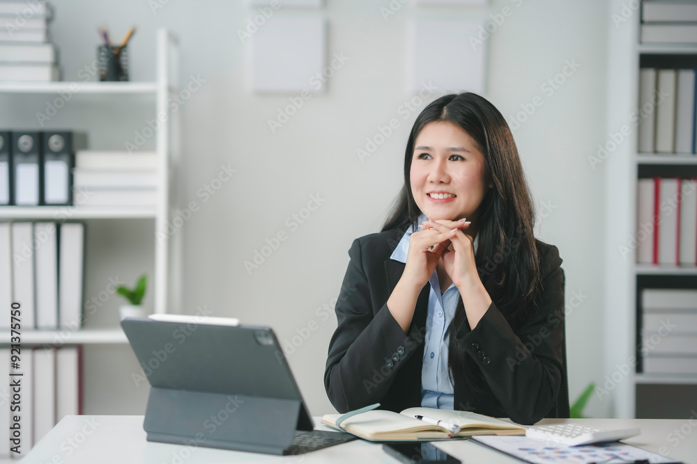 Businesswoman sitting at her desk with hands on chin, smiling and thinking about a new business idea Businesswoman sitting at her desk with hands on chin, smiling and thinking about a new business idea