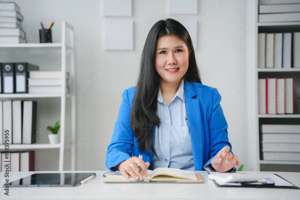Asian businesswoman is sitting at her desk and smiling while working on documents Asian businesswoman is sitting at her desk and smiling while working on documents