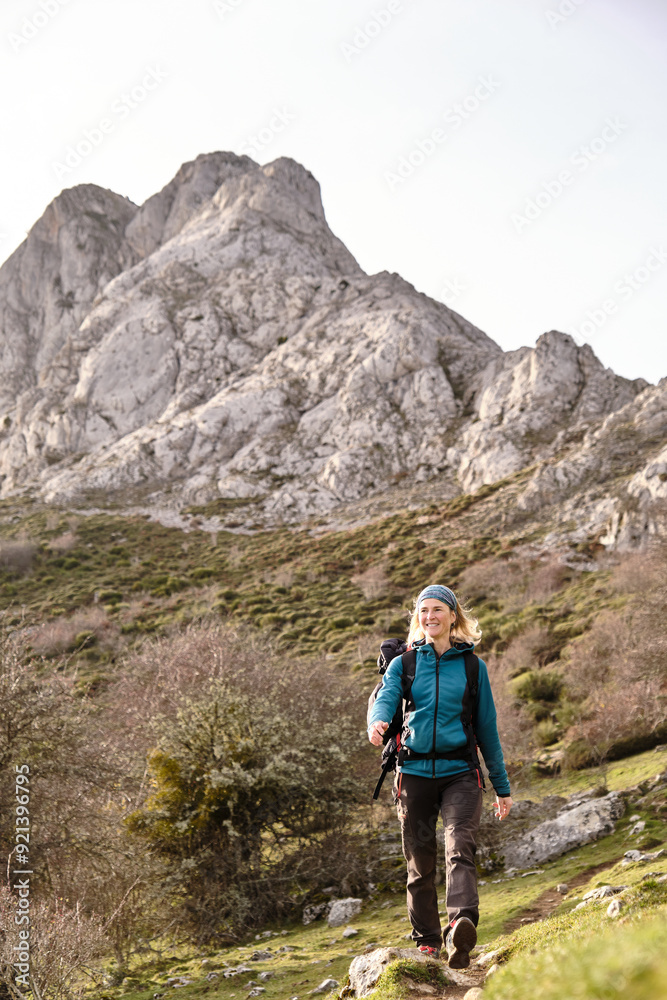 Fototapeta premium Smiling hiker walking with mountain in the background
