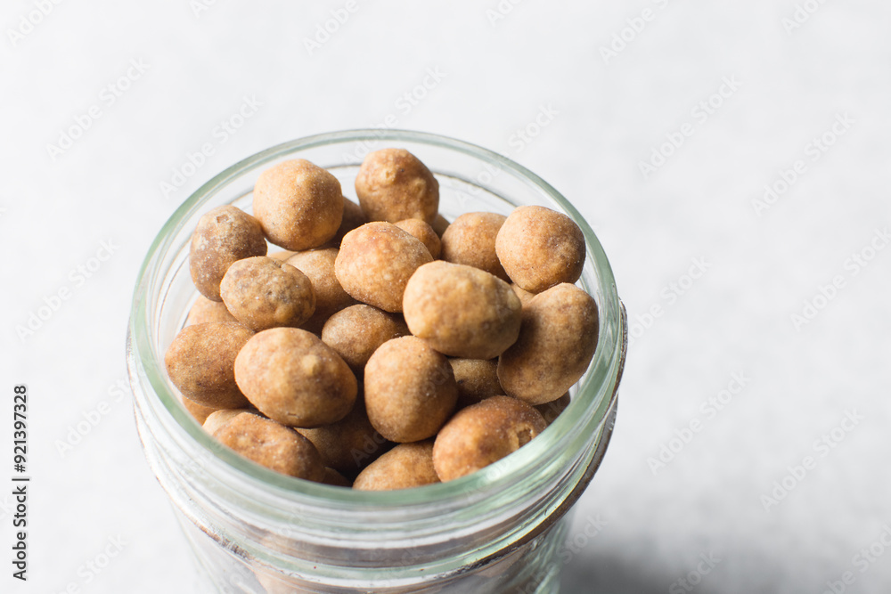 Fried coated peanuts in a glass jar, cracker peanuts on a marble countertop, nigerian peanut snack in a small glass jar Fried coated peanuts in a glass jar, cracker peanuts on a marble countertop, nigerian peanut snack in a small glass jar