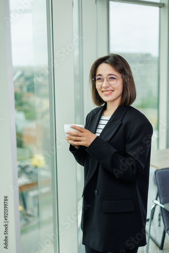 A pretty woman in glasses is standing by the window in a transparent office. A woman rests looking out the window in the office Free Download A pretty woman in glasses is standing by the window in a transparent office. A woman rests looking out the window in the office - GFXLoad