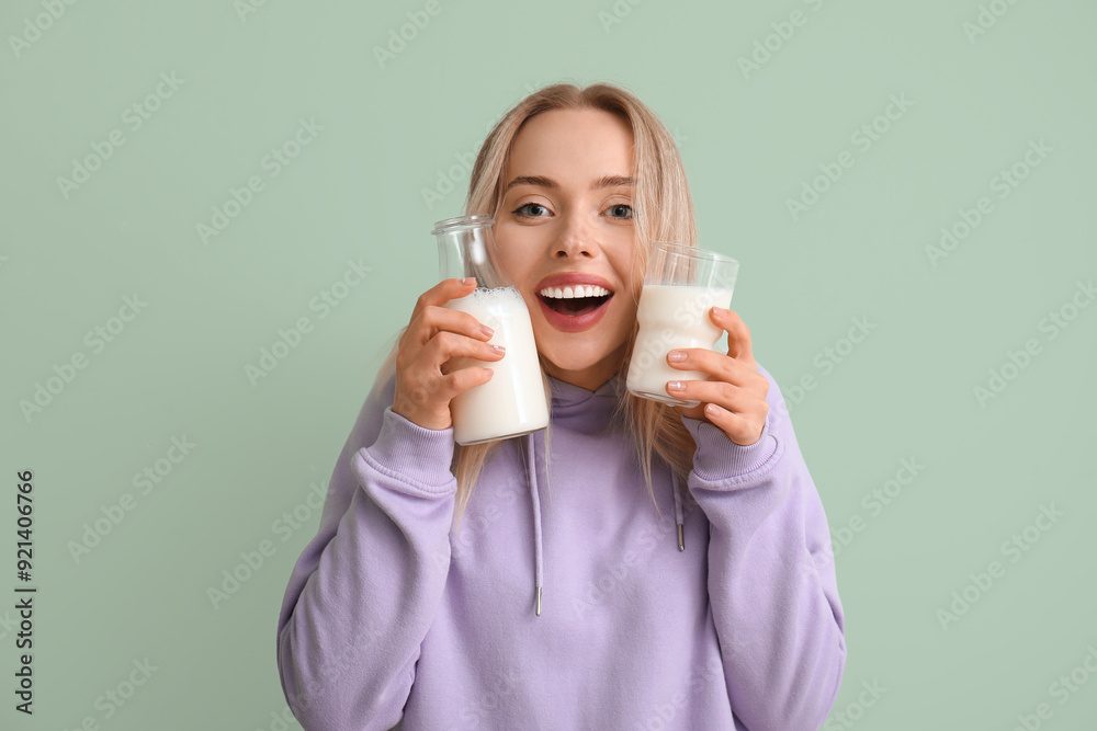 Young woman with glass and bottle of milk on green background Young woman with glass and bottle of milk on green background