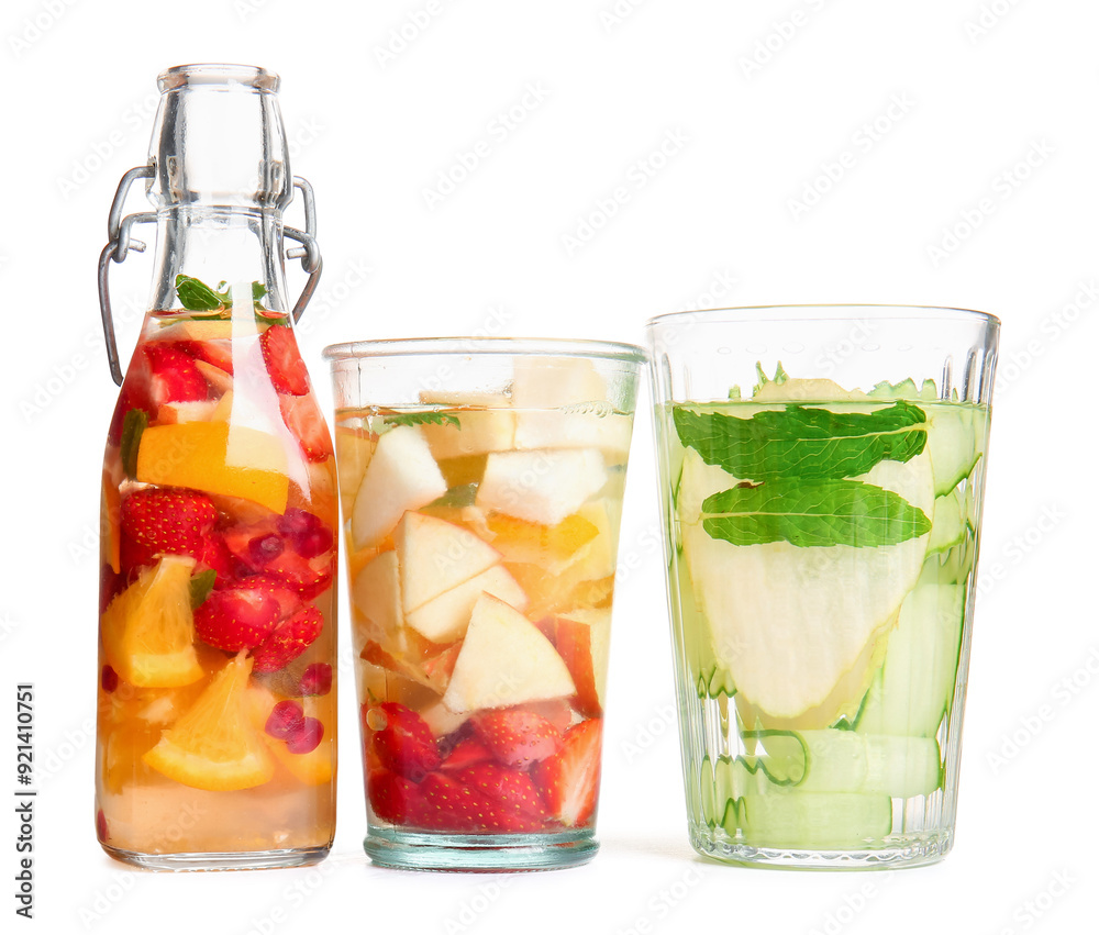 Glasses and bottle of infused water with different sliced fruits on white background Glasses and bottle of infused water with different sliced fruits on white background