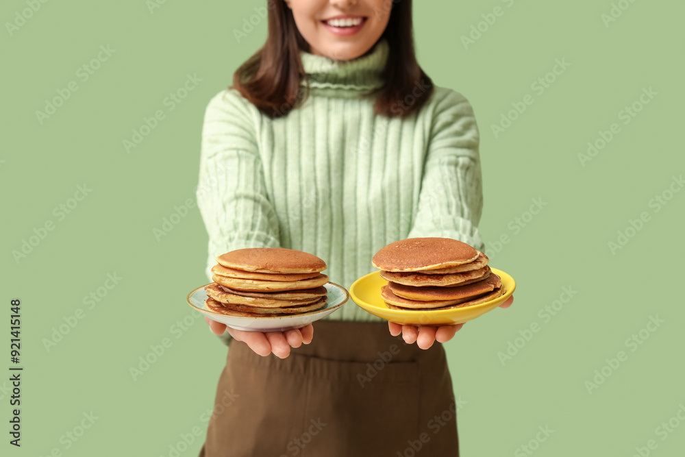Young woman with tasty pancakes on green background Young woman with tasty pancakes on green background