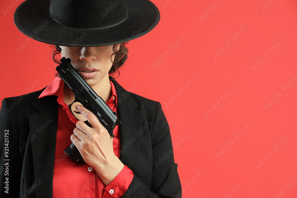 Female African-American spy with gun on red background, closeup