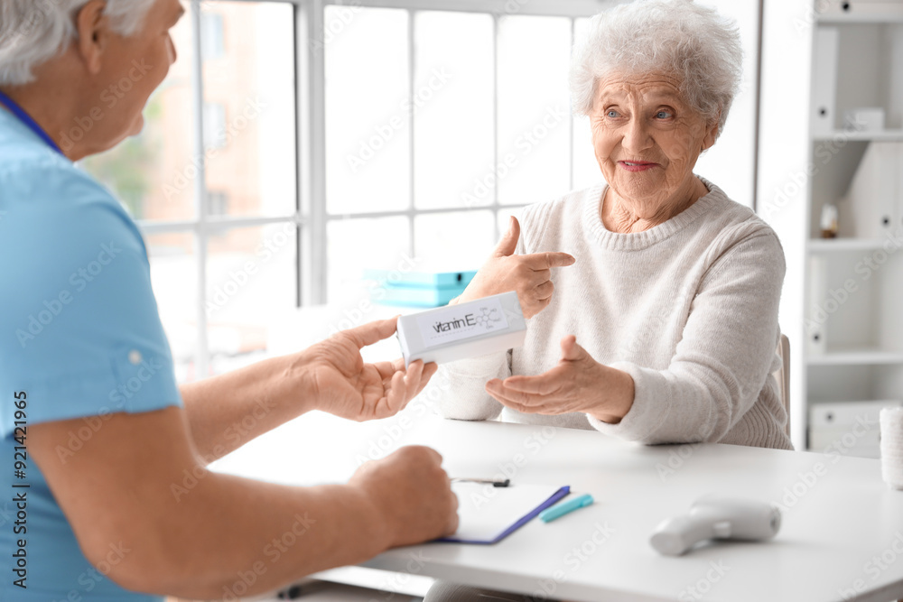 Fototapeta premium Senior woman taking pill box from doctor in clinic