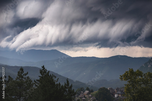 Obraz na płótnie Dramatic view of a hurricane approaching mountainous terrain, with dark, swirling clouds and intense winds. w salonie