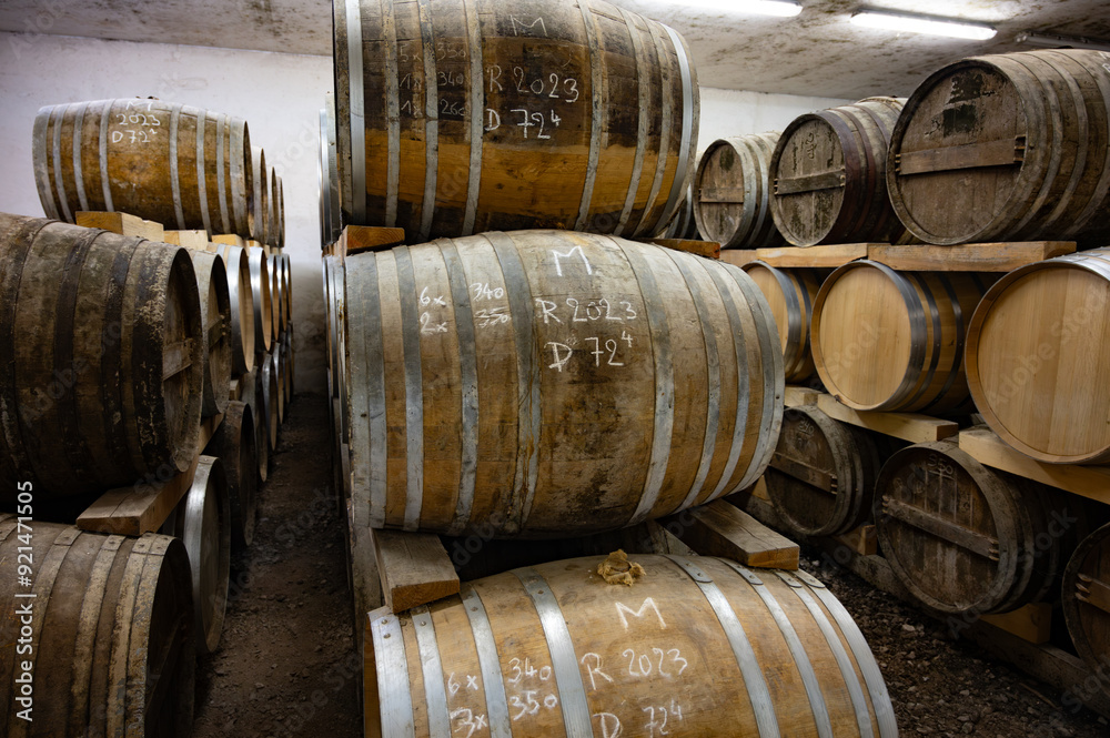 Aging process of cognac spirit in old dark French oak barrels in cellar in distillery house, Cognac white wine region, Charente, Segonzac, Grand Champagne, France Aging process of cognac spirit in old dark French oak barrels in cellar in distillery house, Cognac white wine region, Charente, Segonzac, Grand Champagne, France