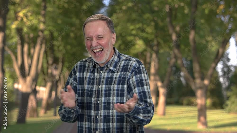 Portrait of handsome mature man laughing out loud. Park trees in the background. Portrait of handsome mature man laughing out loud. Park trees in the background.