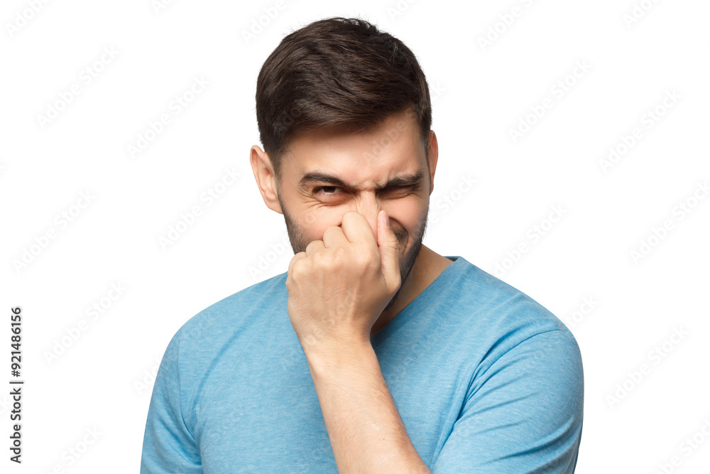 Young man holding his nose as smelling something rotten and stinky, trying to find source of odor Young man holding his nose as smelling something rotten and stinky, trying to find source of odor