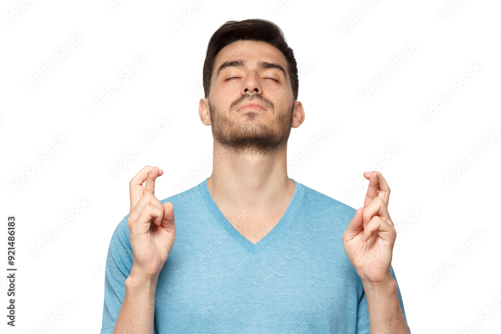 Young man with eyes closed and crossed fingers of both hands, wishing luck