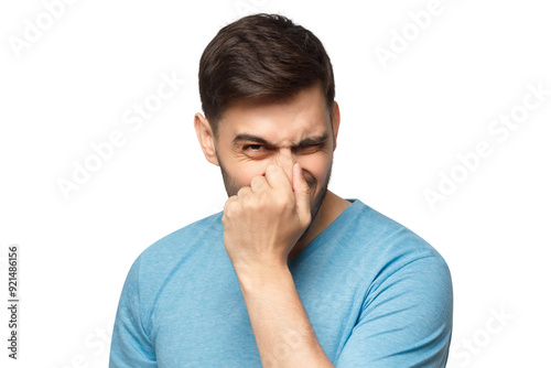 Young man holding his nose as smelling something rotten and stinky, trying to find source of odor